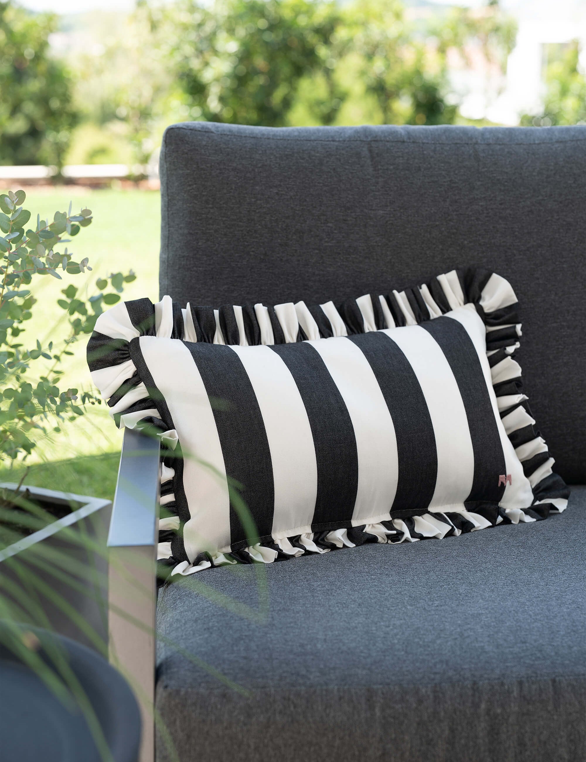 another mondaen Outdoor Kissen Ruffled Charm Graphit auf Gartenlounge – schwarz-weiß gestreifte Designkissen für Terrasse und Garten aus der VACANCES Outdoor Kollektion