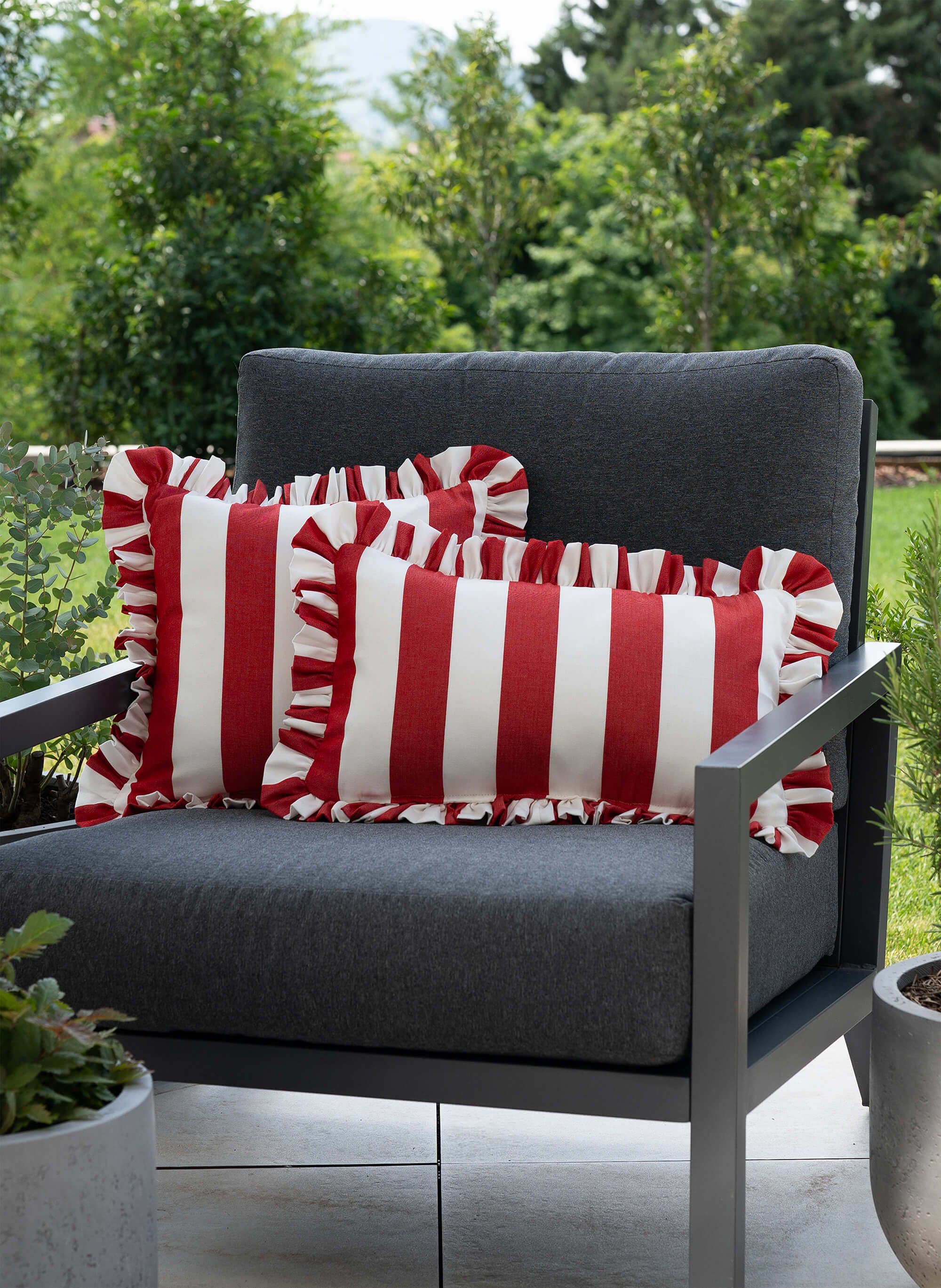 another mondaen Outdoor Kissen Ruffled Charm Red auf Gartenlounge – rot-weiß gestreifte Designkissen für Terrasse und Garten aus der VACANCES Outdoor Kollektion
