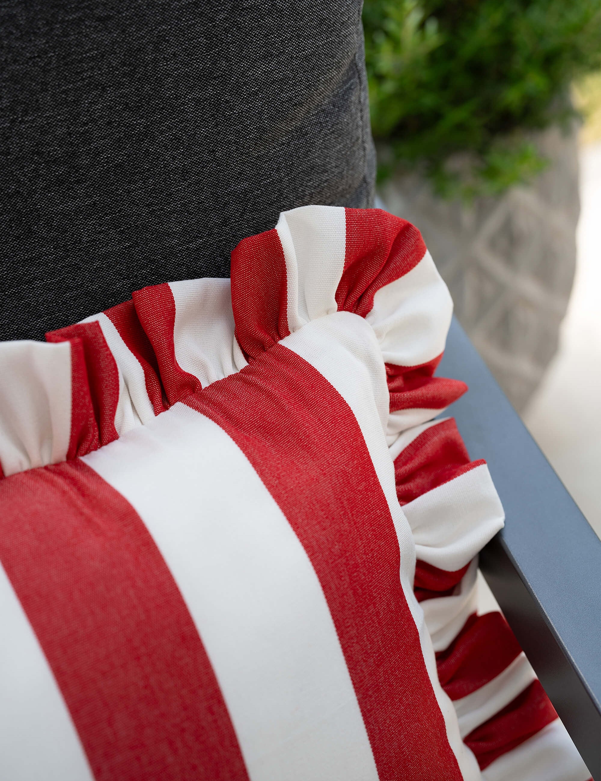 another mondaen Outdoor Kissen Ruffled Charm Forest auf Gartenlounge – rot-weiß gestreifte Designkissen für Terrasse und Garten aus der VACANCES Outdoor Kollektion