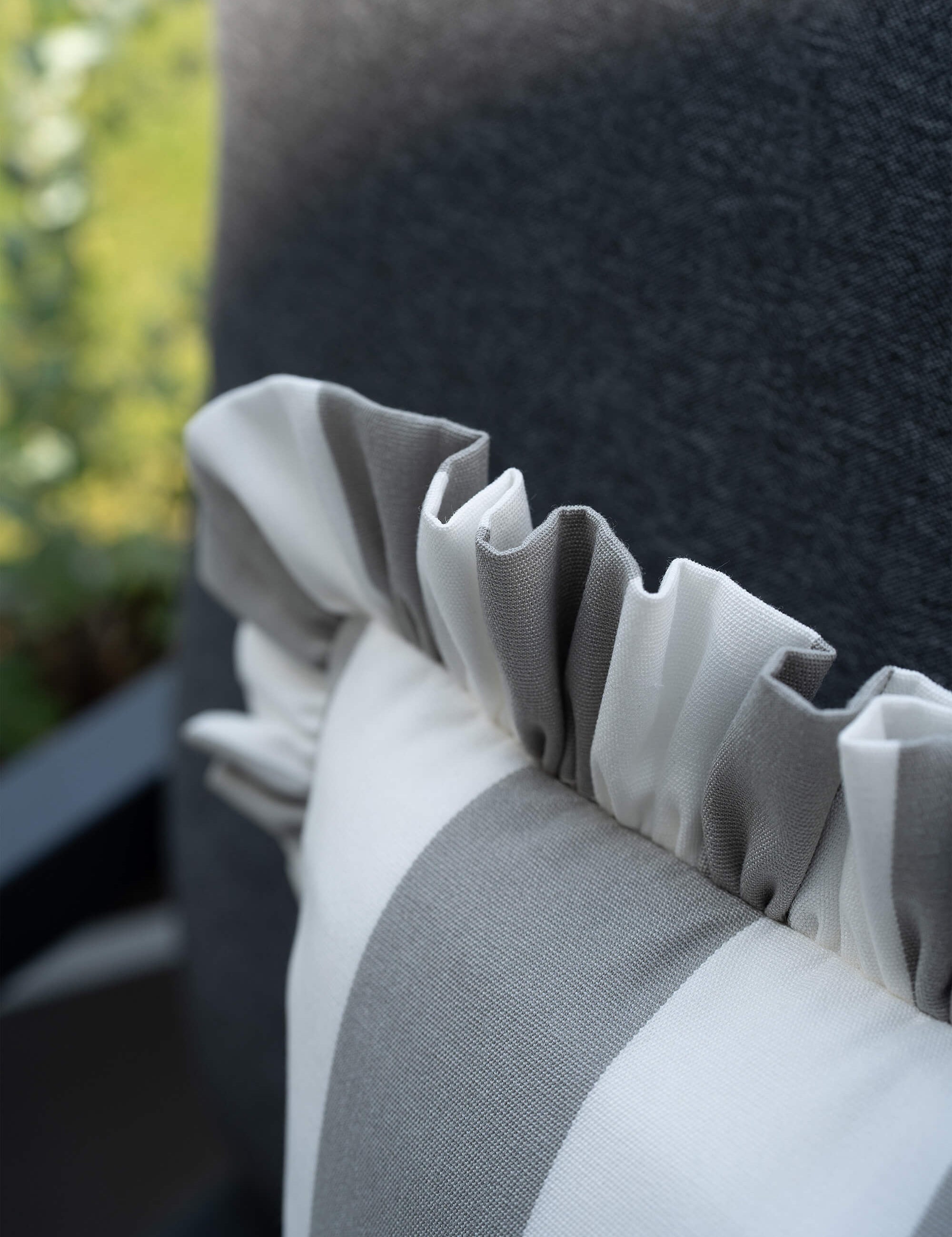 Detailaufnahme des another mondaen Outdoor Kissens Ruffled Charm Stone – grau-weiß gestreifter Outdoor Stoff mit handgefertigter Rüschenkante