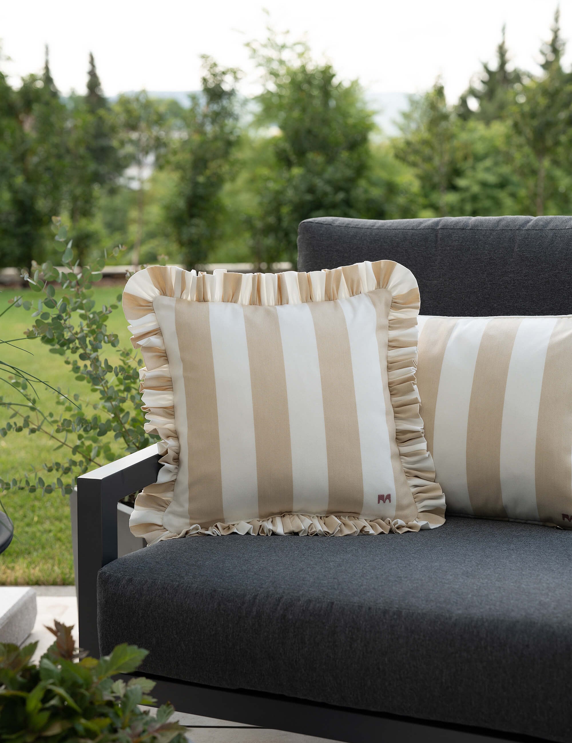 another mondaen Outdoor Kissen Ruffled Charm Beige auf Gartenlounge – beigen-weiß gestreifte Designkissen für Terrasse und Garten aus der VACANCES Outdoor Kollektion