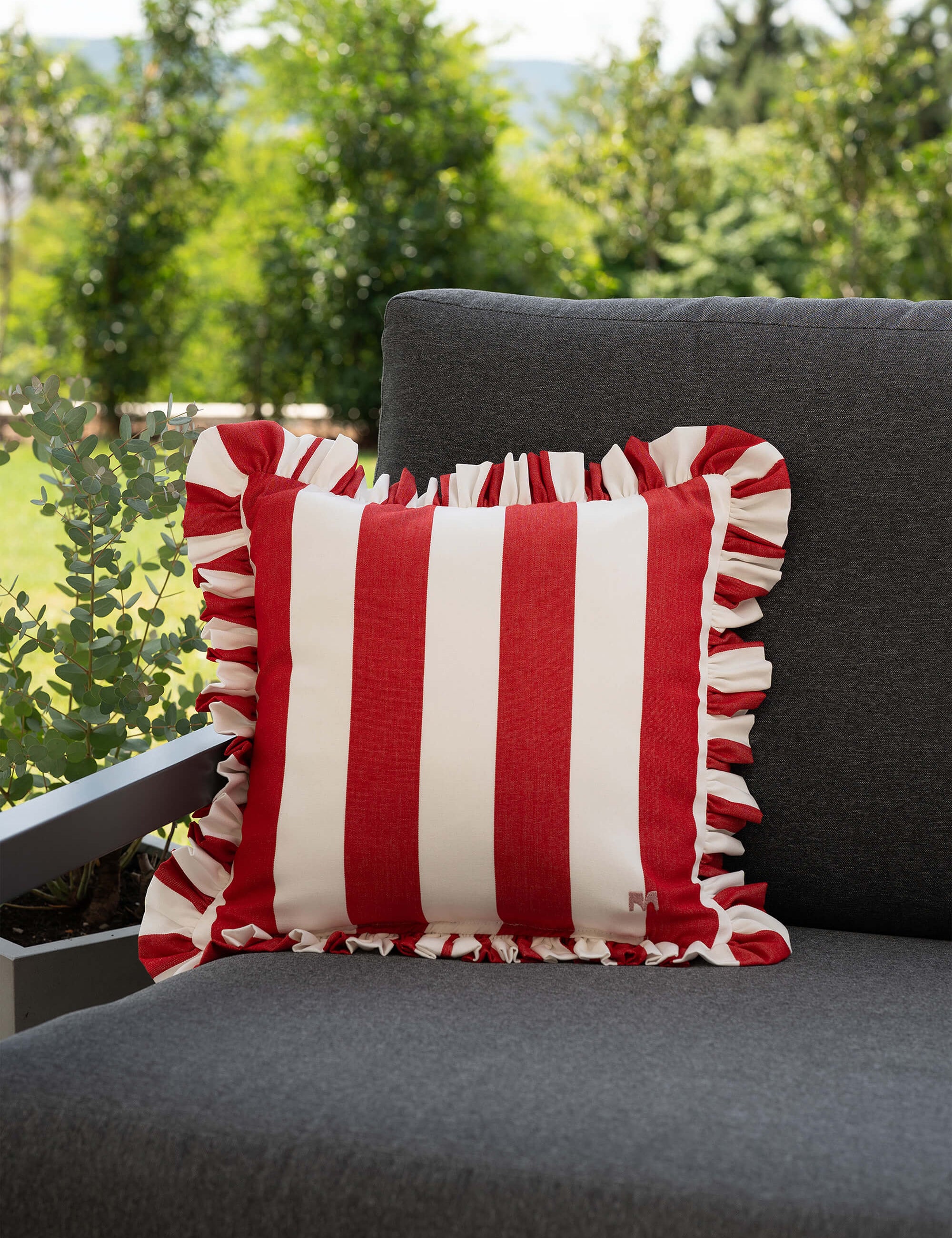 another mondaen Outdoor Kissen Ruffled Charm Red auf Gartenlounge – rot-weiß gestreifte Designkissen für Terrasse und Garten aus der VACANCES Outdoor Kollektion