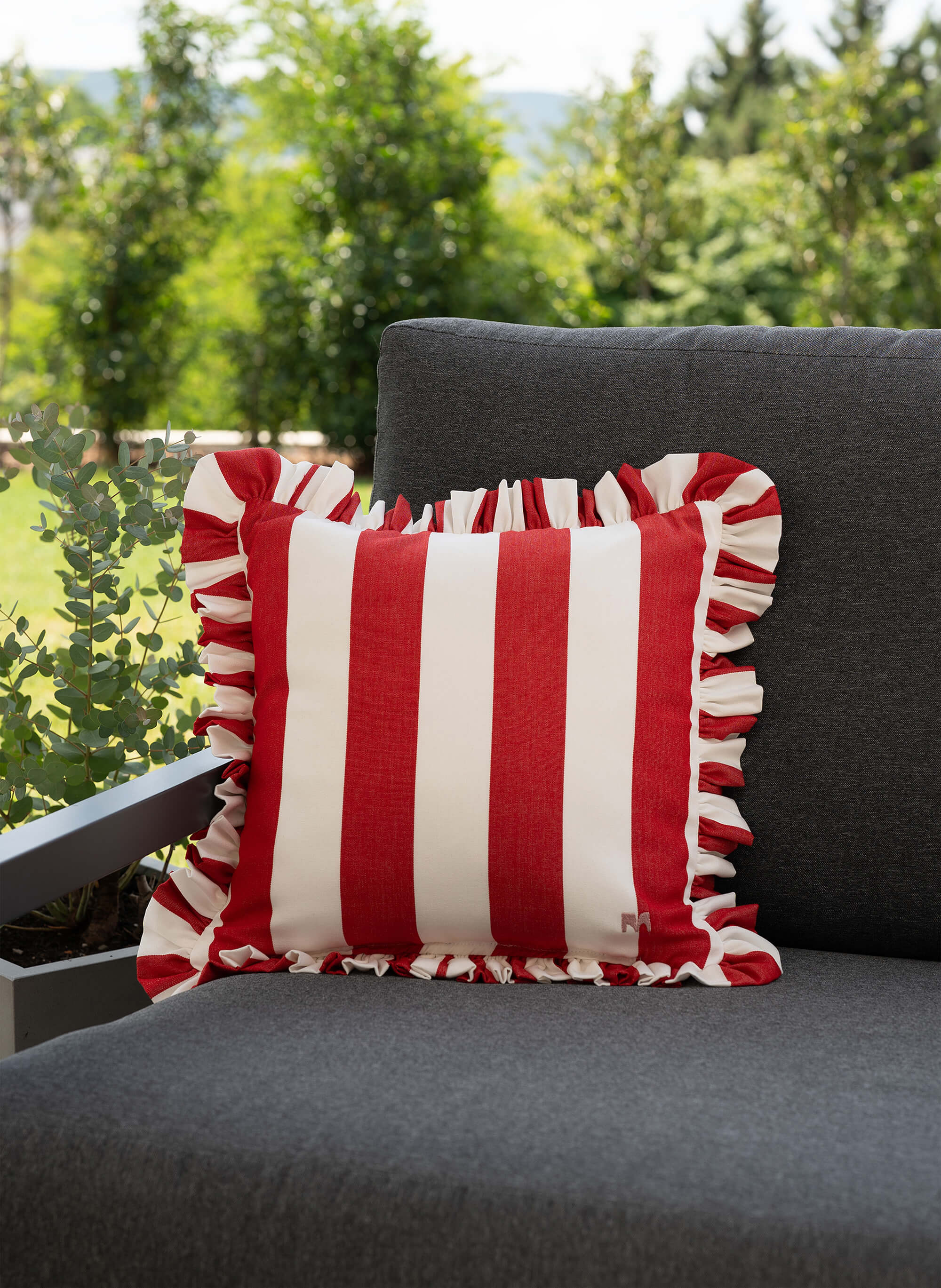 another mondaen Outdoor Kissen Ruffled Charm Red auf Gartenlounge – rot-weiß gestreifte Designkissen für Terrasse und Garten aus der VACANCES Outdoor Kollektion