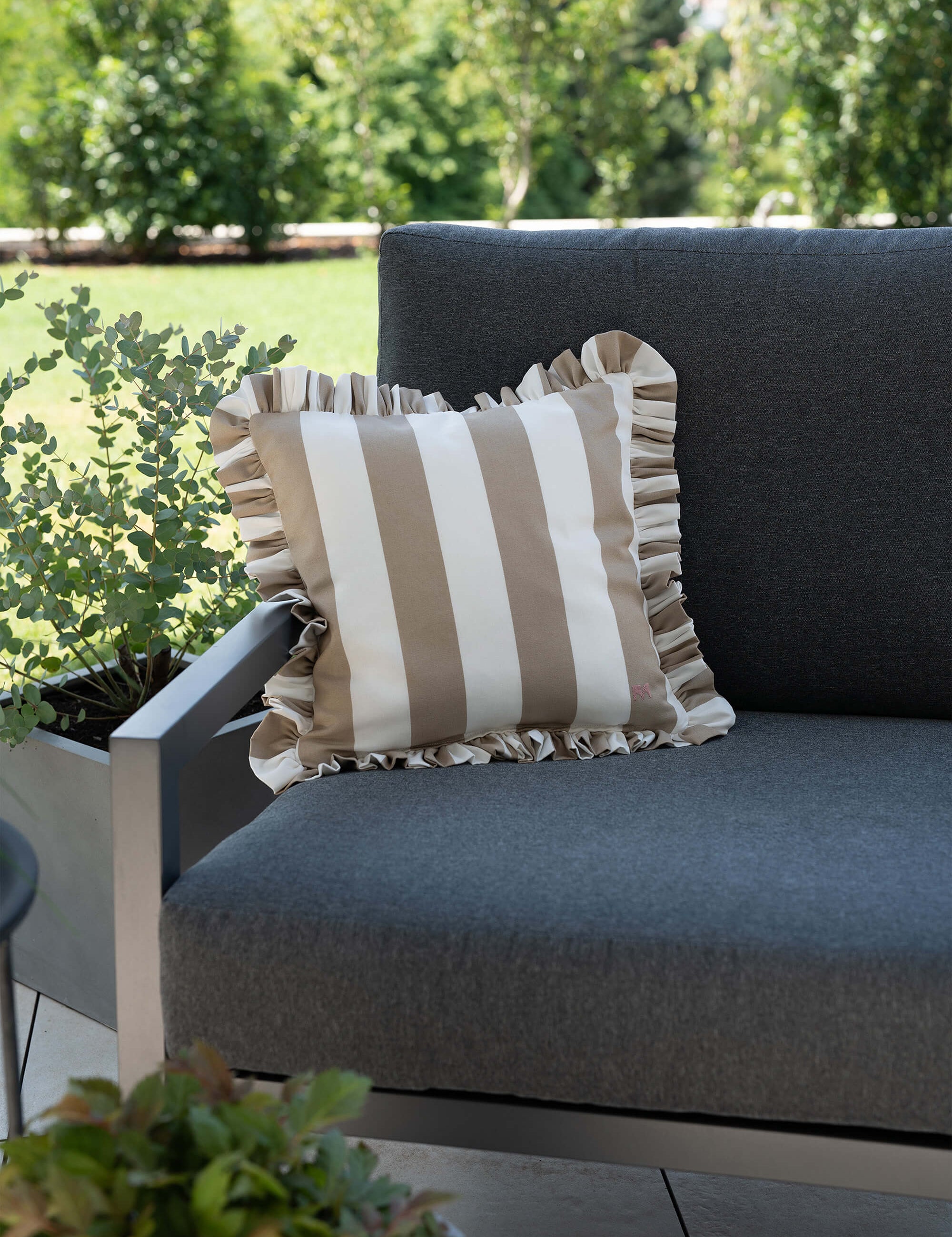 another mondaen Outdoor Kissen Ruffled Charm Taupe auf Gartenlounge – Taupe-weiß gestreifte Designkissen für Terrasse und Garten aus der VACANCES Outdoor Kollektion