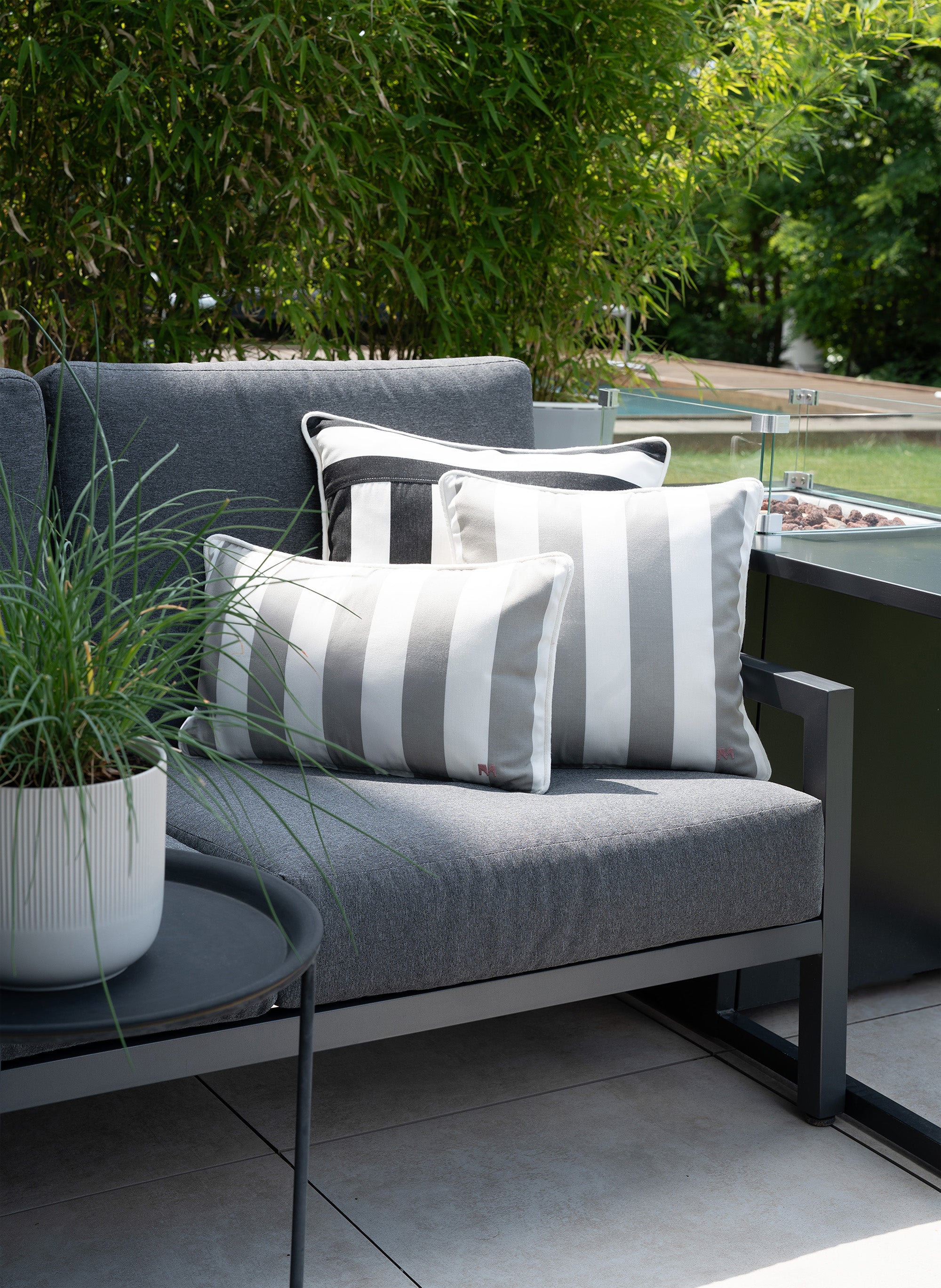 Outdoor Lounge mit grau-weiß gestreiften Kissen von another mondaen auf moderner Terrasse – hochwertige Outdoor-Kissen in sommerlicher Gartenatmosphäre mit wasserabweisendem Stoff.